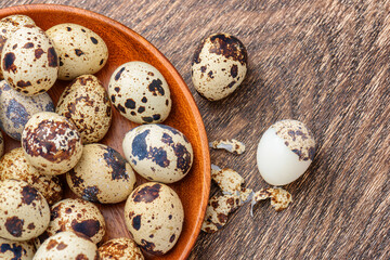 Fototapeta premium Top view of quail eggs in wooden plate on table