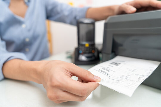 Close-up, Hand of Asian woman worker uses a laptop or notebook to print bar code stickers on a bar code printer.