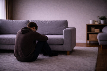 Obraz premium Man sitting on floor near sofa, feeling stuck and life pause concept