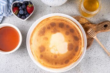 Homemade french tiny pancakes, battercakes with berries and honey. Stack of freshly baked...