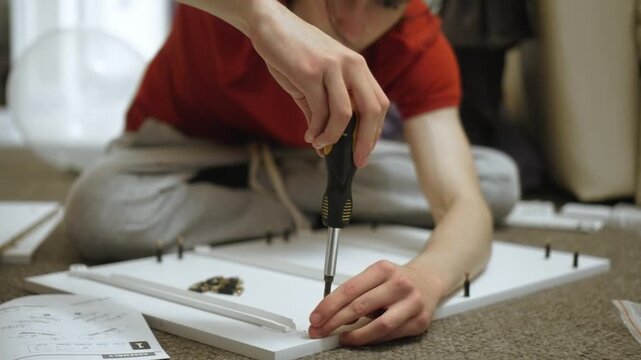 Assembling drawer panel with connector hardware during dresser building. Constructing furniture board with fastening elements while crafting DIY cabinet. Working on woodworking project with assembly