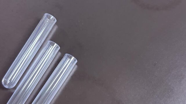 Transparent test tubes with subtle movement on lab bench, left composition