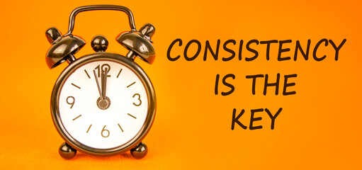 Naklejka premium Consistency is the key symbol. Concept words Consistency is the key on beautiful orange paper. Beautiful orange paper background. Black alarm clock. Business consistency is the key concept. Copy space