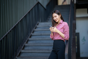 Fototapeta premium Woman smiling using smartphone on urban stairs