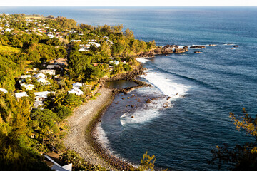 Obraz premium Piscine naturelle sur une plage de galets protégée des vagues devant un village, vue de haut. Manapany les bains, sud île de la Réunion