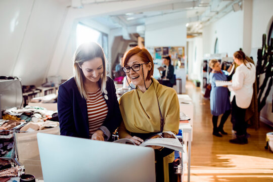 Two female fashion designers collaborating in loft studio