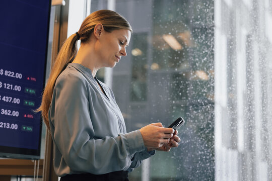 Stock trader looking at phone on a grey rainy day