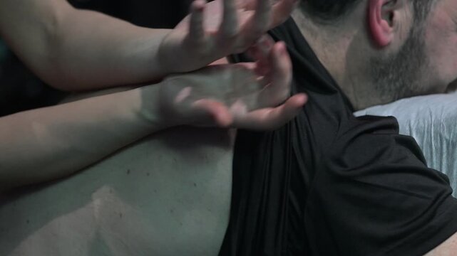 A person receives a massage in a spa. One therapist uses their hands to apply pressure on the back to promote relaxation and release tension