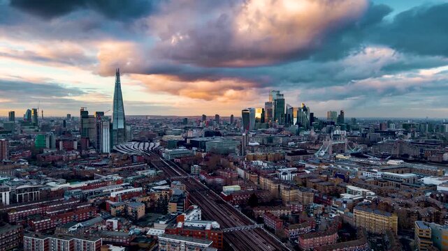 Aerial hyperlapse view of the London cityscape with Tower Bridge, train traffic and skyscrapers during sunset with dramatic cloudscape