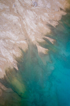 Aerial view of the meeting point of earth and water, where the rugged, light earth meets the calm, dark turquoise waters, Trento, Trentino-Alto Adige, Italy.