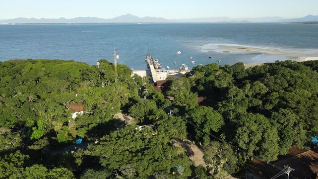 Voo de drone sobre Ilha do Mel do lado de Bras&iacute;lia no Litoral do Paran&aacute; no mangue no trapiche de embarca&ccedil;&otilde;es com mar oceano atl&acirc;ntico azul em Paranagu&aacute;