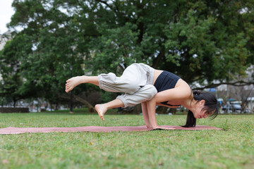 Woman practicing outdoor yoga exercise in green park
