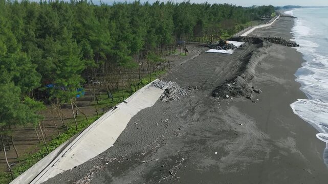 This video documents a breached coastal seawall where large sections have broken apart and separated under continuous wave pressure.