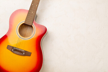 Fototapeta premium Bright acoustic guitar on concrete background, top view