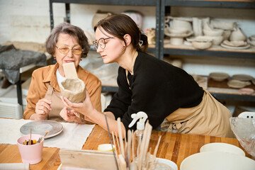 Craftswoman teaches pensioner to make bowl from raw clay