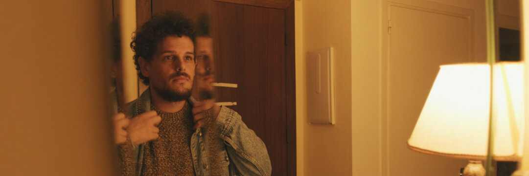 Close-up of an unshaven guy looking at himself in the mirror. Panoramic