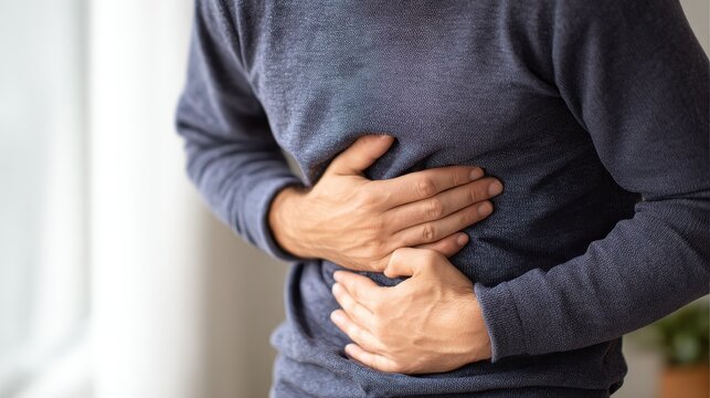 Patient holding abdomen with discomfort caused by ascites related to advanced liver cirrhosis