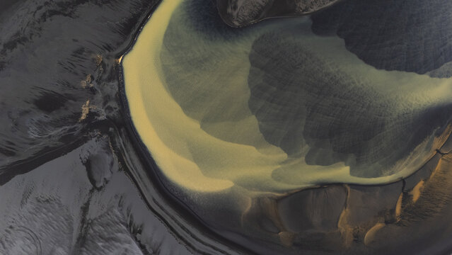 Aerial view of swirling glacial river patterns create a mesmerizing dance of ochre and slate, etching a stark yet beautiful landscape, Selfoss, Iceland.