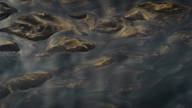 Aerial view of glacial river's braided channels weave through the landscape, creating a mesmerizing mosaic of dark waters and sandy banks, Selfoss, Iceland.