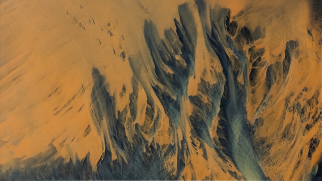Aerial view of the land patterned with dark and light shades, creating a dramatic landscape of textures and tones, Selfoss, Iceland.