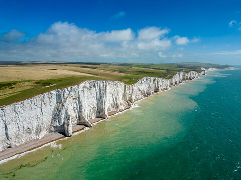 Aerial view of the chalk cliffs plunge dramatically into the turquoise sea, the iconic Seven Sisters standing sentinel against the horizon, Seaford, England, United Kingdom.