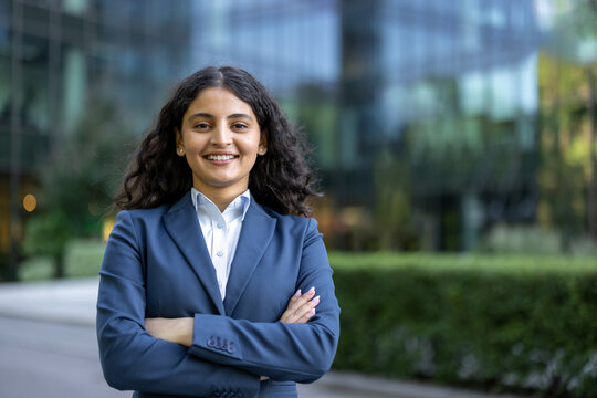 Young businesswoman smiling with arms crossed in corporate setting