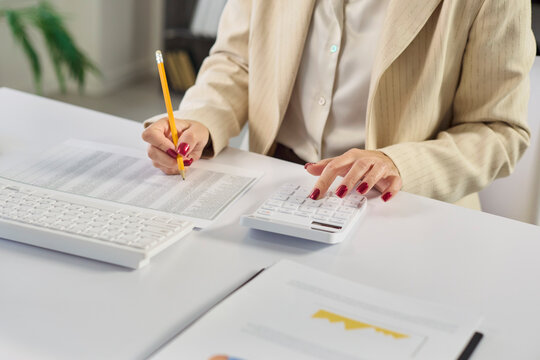 Accountant audit finance analysis in office with computer. Female woman reviews paperwork and enters numbers on calculator for financial statements at desk. Clear audit and finance concept.