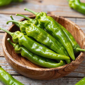Ripe green chili peppers in a rustic wooden bowl