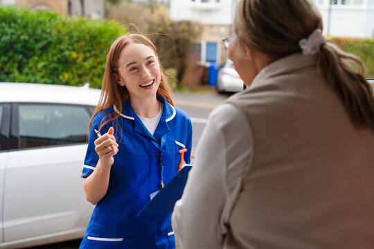 Young female healthcare worker talks to an elderly woman at her home in a friendly visit