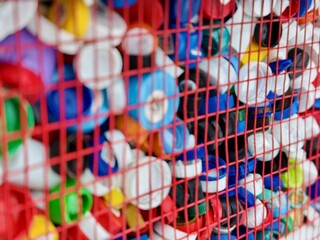 Fototapeta premium Vivid Lid Collection. Brightly Colored Lids Arranged In Wire Basket For Upcycling. Visual Display Of Assorted Bottle Tops Promoting Reuse And Sustainable Waste Management Practices