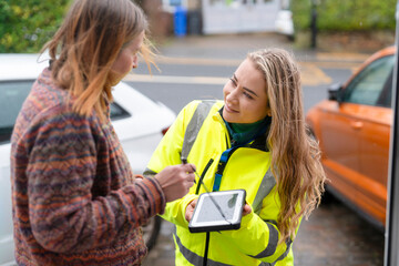 Two people talking outside with a tablet on a street in a residential area © Iryna