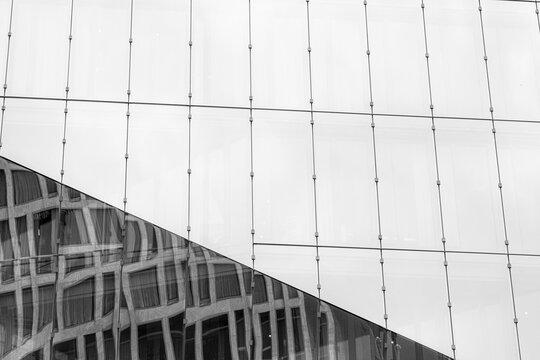 Monochrome modern glass facade with grid pattern and curves forming urban architecture structure for minimal editorial background and design use