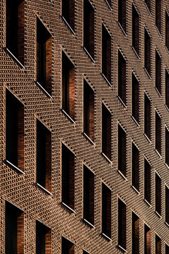 Brick facade pattern with rich texture and deep shadow showing urban architecture repetition and geometry in close detail for background design
