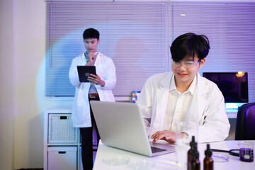 Obraz premium Diverse scientists collaborating in a modern laboratory, conducting research with a laptop, microscope, and chemical experiments