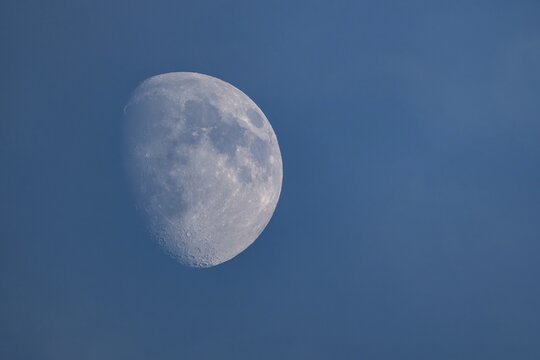 Detailed image of the waxing moon with visible craters and spots during the day, dividing line between the day and night sides of the moon visible, Finland