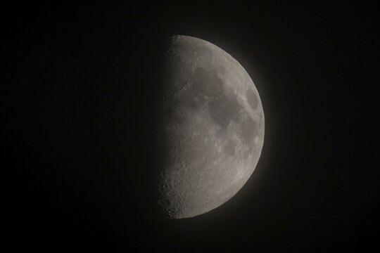 Detailed image of the waxing moon with visible craters and spots at night, dividing line between the day and night sides of the moon