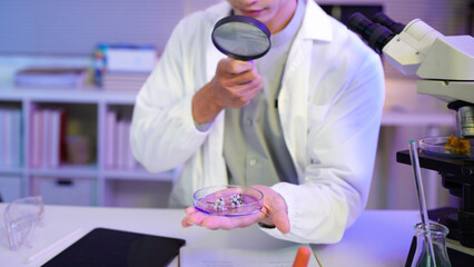 scientist examines petri dish sample with magnifying glass, laboratory inspection, microbiological...