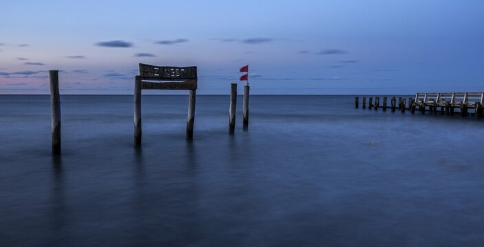Wooden sign in the sea with inscription Zingst and wooden walkway, long exposure, evening light, Zingst, Fischland-Dar&szlig;-Zingst, Western Pomerania National Park, Mecklenburg-Western Pomerania, Germany