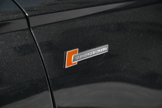 Supercharged badges on the rear of an Audi S6. Close-up view of performance model emblems highlighting automotive branding, engine technology, and premium sports sedan in Durres, Albania 10.11.2025