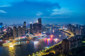 Obraz premium Vibrant night view of Chongqing city skyline with illuminated skyscrapers and cruise boats on the river in China.