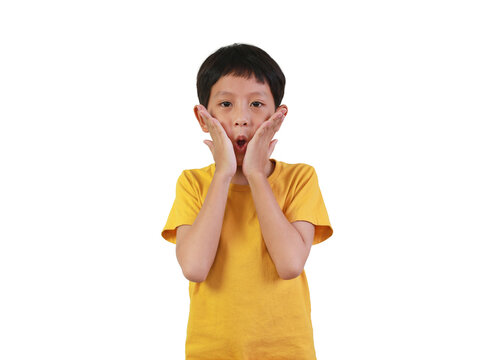 A surprised little Asian boy in yellow t-shirt touching his cheeks with an open mouth and shocked expression, isolated on white background.