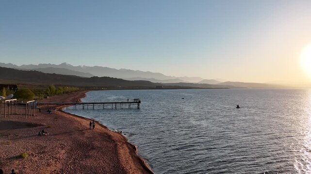 Stunning drone view of Issyk-Kul Lake at sunset, showcasing golden skies
