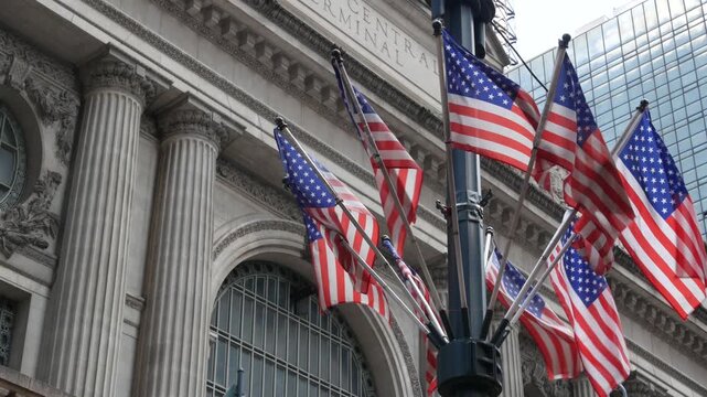 American flags near Grand Central Terminal on 42 street, New York City, Manhattan Midtown. Railway building architecture in United States. Public railroad transport junction. Old station exterior.