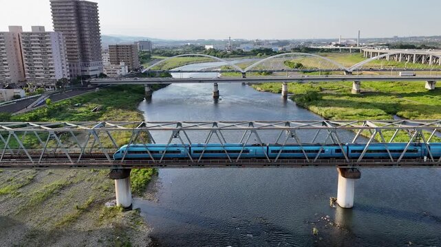 Aerial view of the bule Odakyu Romancecar MSE train crossing a bridge.