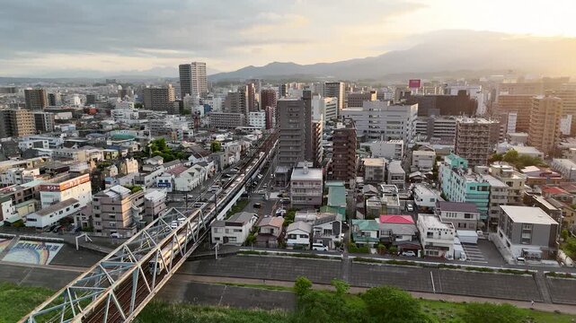Cinematic drone shot of a Japanese train traveling over a river bridge. 