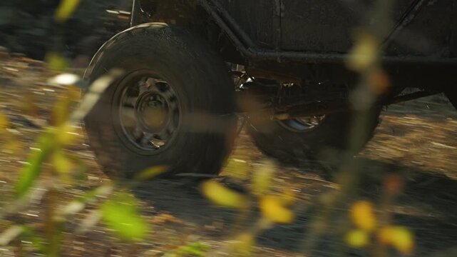 The wheel of a dirty Off-road vehicle in motion over rough terrain from a low angle. The rotating tire transmits speed and power during off-road competition. Slow motion
