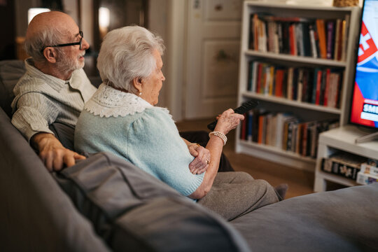 Lovely senior couple watching television in the evening.