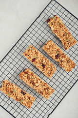 Gluten-free oat granola bars with nuts and berries on a black cooling rack