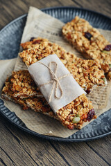 Gluten-free oat granola bars with nuts and berries on round vintage metal tray