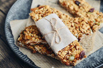 Gluten-free oat granola bars with nuts and berries on round vintage metal tray
